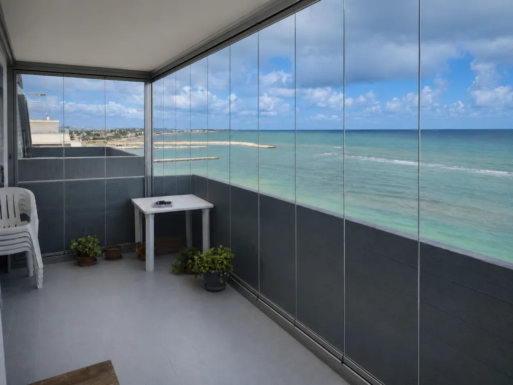 Balcone fronte mare chiuso con vetrate panoramiche trasparenti, con vista sulla costa e sul mare
